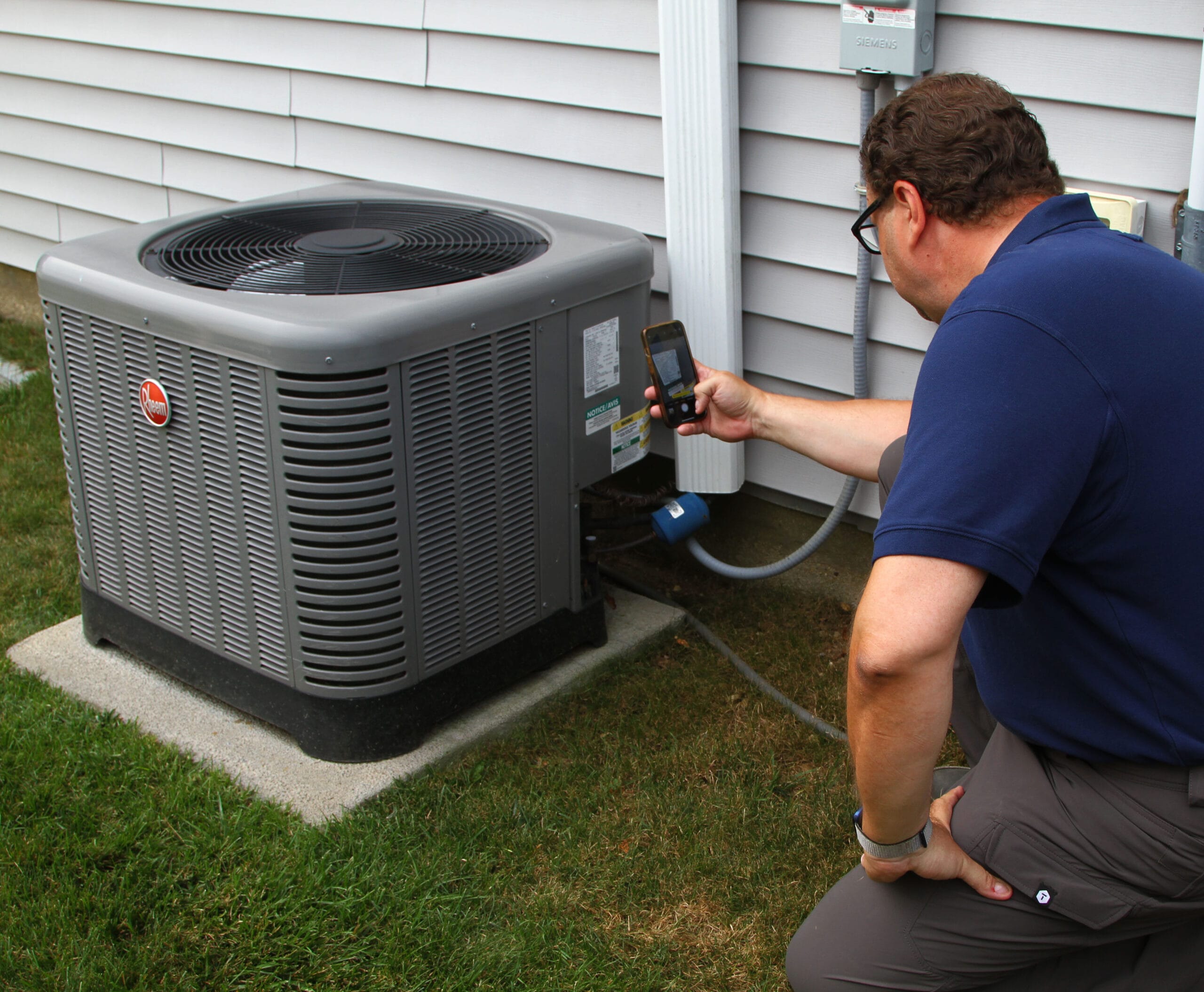 home inspector Joe capturing a photo of an AC condenser unit on the side of a home